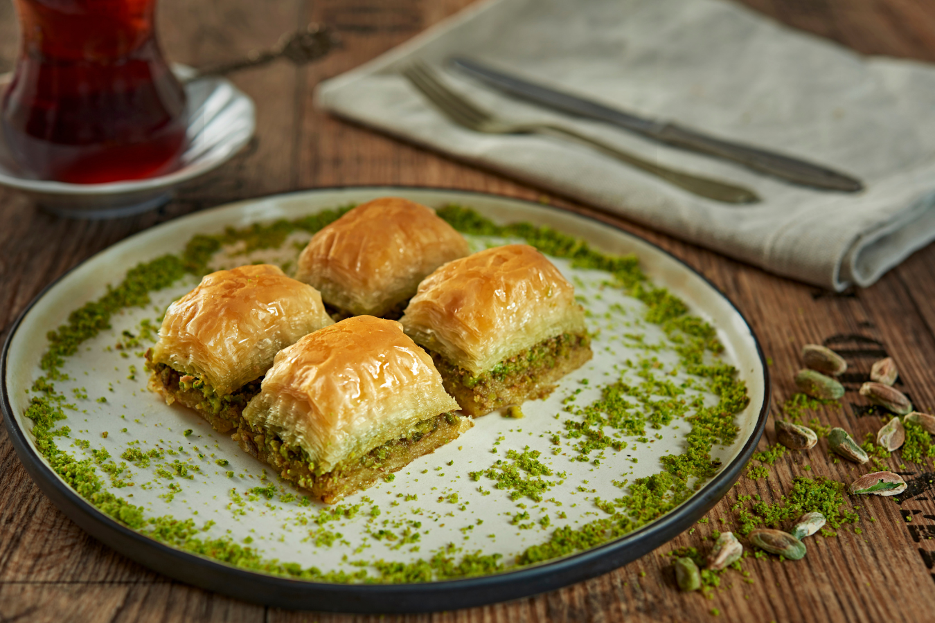 Baklava on a plate with a side of tea on a wooden table