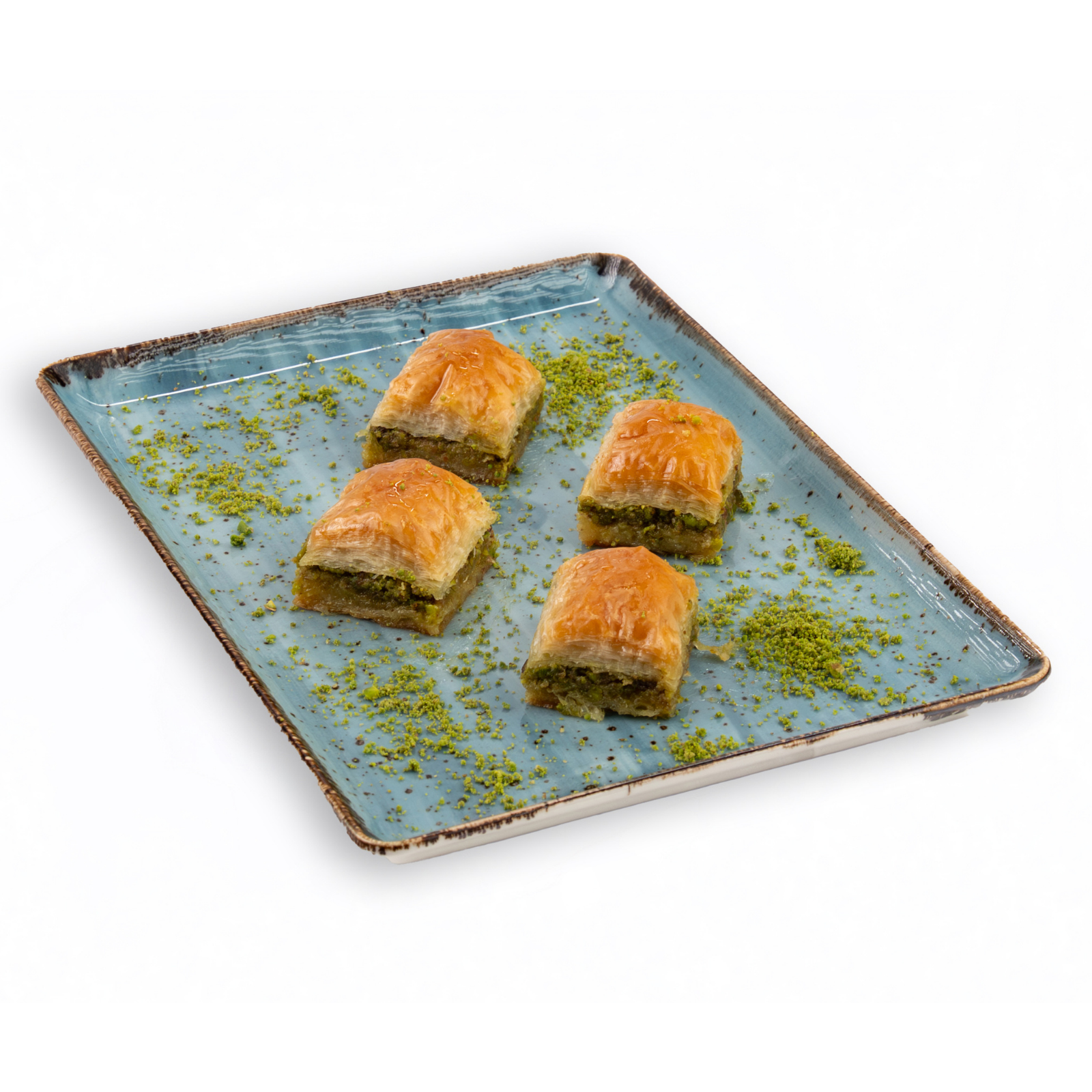 Four pieces of baklava on a decorative plate with green pistachio sprinkles.