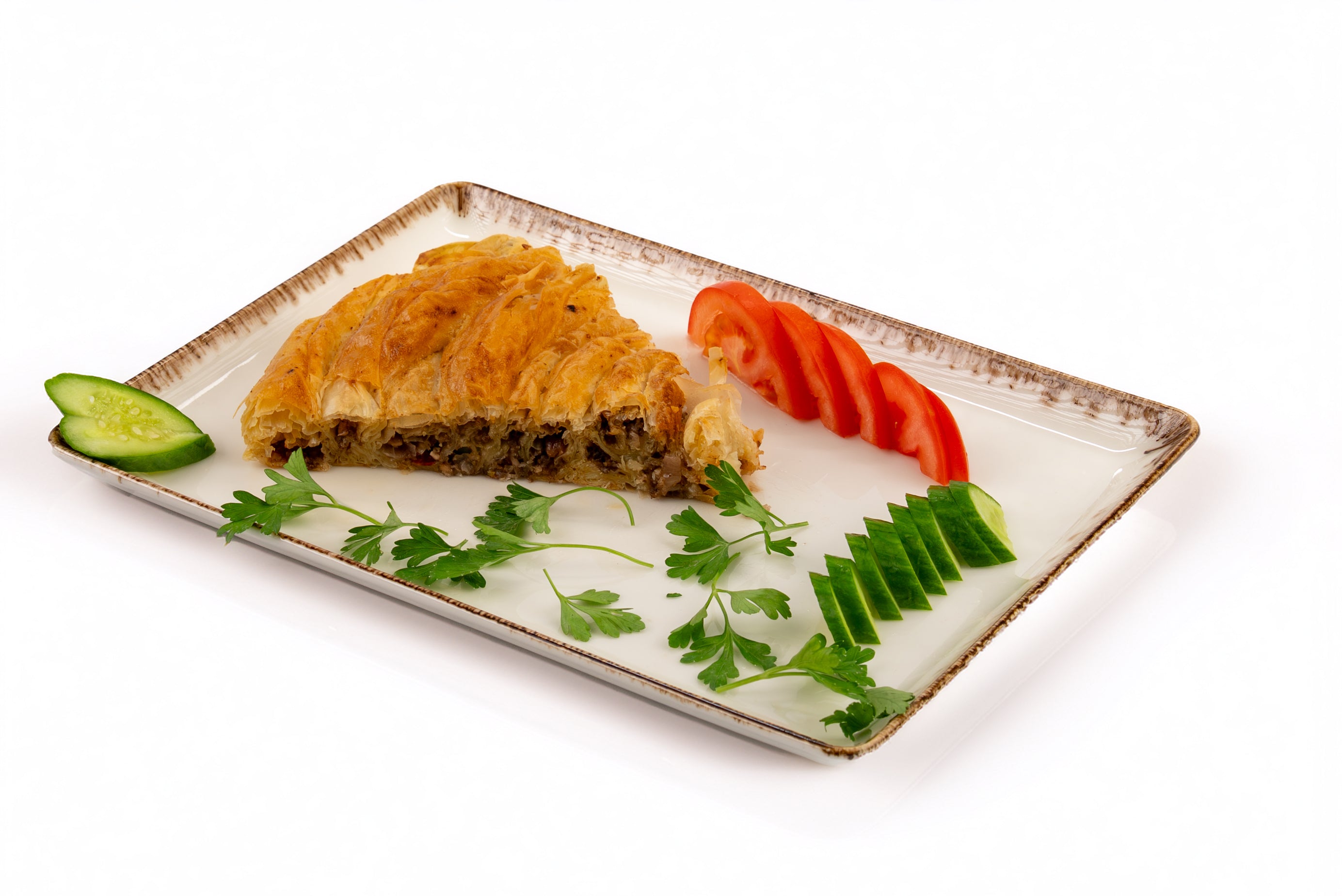 Plated dish with a pastry and vegetables on a white background